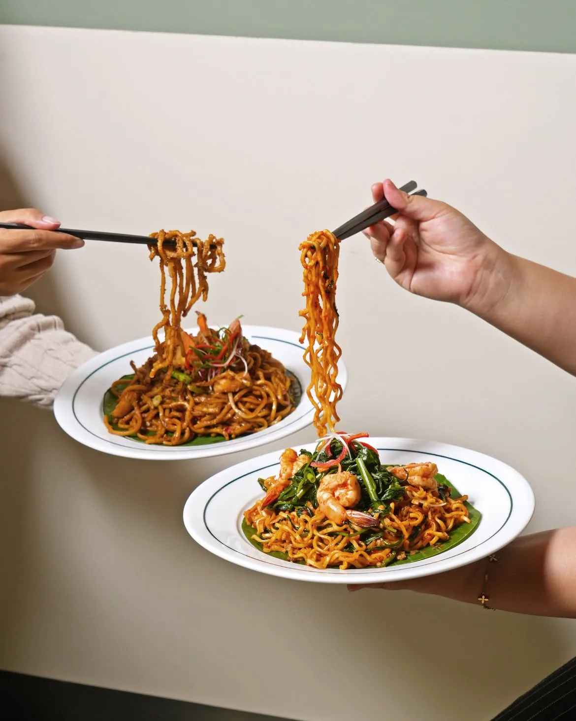 Two guests lifting prawn and chicken fried noodles with chopsticks